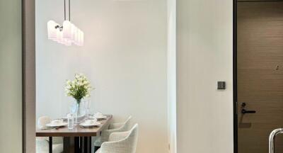 Modern dining area with a wooden table and upholstered chairs, decorated with a flower vase and set for meal