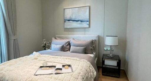 Modern bedroom with a bed, nightstand, lamp, and artwork