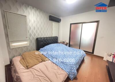 Bedroom with wooden floor, double bed, nightstand, and glass sliding doors