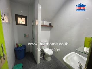 Bathroom with toilet, sink, and wall-mounted shelf