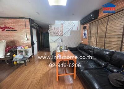 Living room with black leather sofa and wooden floor