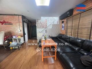 Living room with black leather sofa and wooden floor