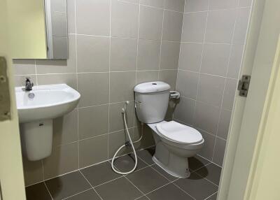 Clean bathroom with sink, toilet, and a hand-held bidet sprayer