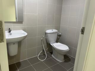 Clean bathroom with sink, toilet, and a hand-held bidet sprayer