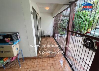 Covered entrance of building with tiled floor, metal fence, and storage items