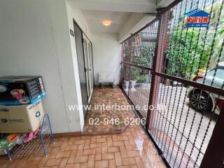 Covered entrance of building with tiled floor, metal fence, and storage items