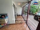 Covered entrance of building with tiled floor, metal fence, and storage items