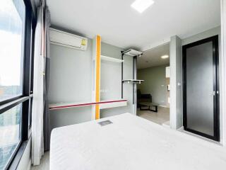 Modern bedroom with large windows, air conditioning, and built-in shelving.