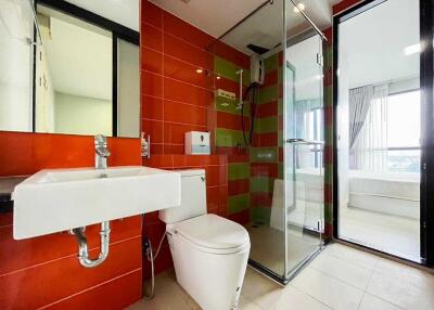 Modern bathroom with red tiles, white sink, and glass shower enclosure