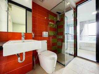 Modern bathroom with red tiles, white sink, and glass shower enclosure