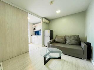 Living room with a sofa, glass coffee table, and partial view of the kitchen