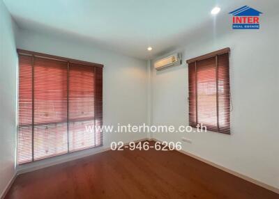 Empty bedroom with wooden floors and large windows