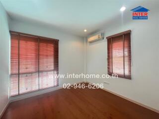 Empty bedroom with wooden floors and large windows