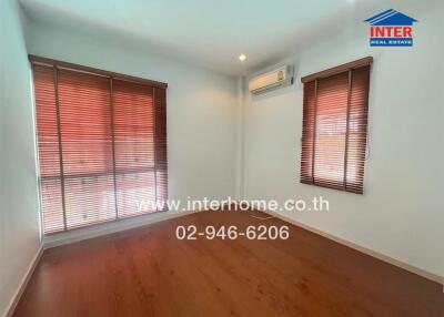 Bright bedroom with wooden floor and large windows with blinds