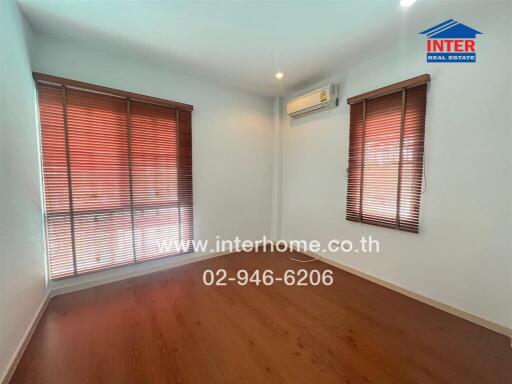 Bright bedroom with wooden floor and large windows with blinds