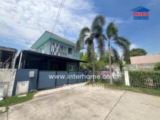 Two-story residential building with driveway and palm trees