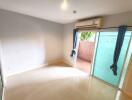 Empty bedroom with sliding door leading to a small balcony