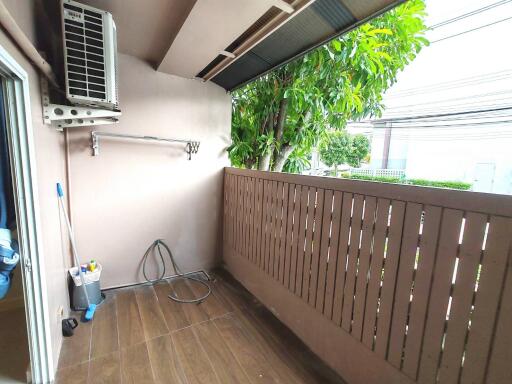 Simple balcony with wooden railings, air conditioning unit, and a view of greenery