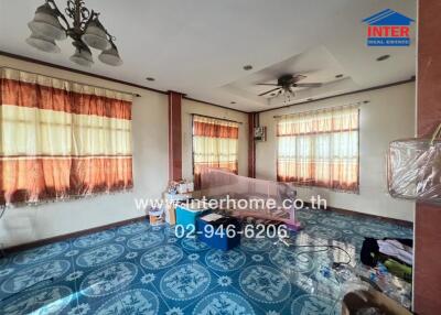 Spacious living room with blue tile flooring and large windows with curtains.