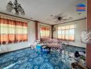 Spacious living room with blue tile flooring and large windows with curtains.