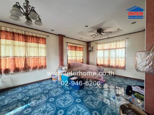 Spacious living room with blue tile flooring and large windows with curtains.