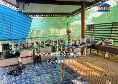 Covered outdoor patio area with cooking utensils and bamboo seating