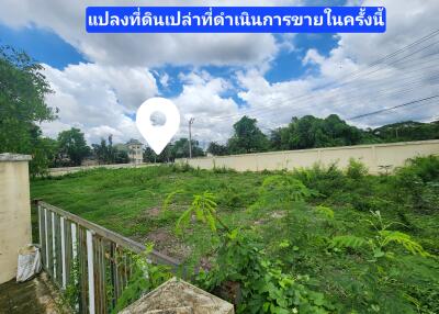 Open plot of land under bright blue sky with a nearby residential area
