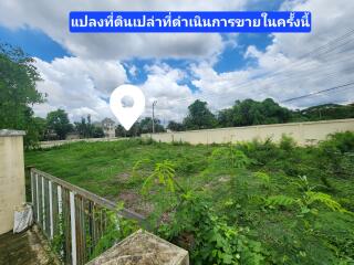 Open plot of land under bright blue sky with a nearby residential area