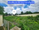 Open plot of land under bright blue sky with a nearby residential area