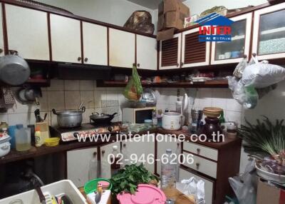 A cluttered kitchen with various cooking utensils and food items.