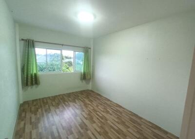 Empty bedroom with wooden floor and window with curtains