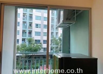 Sliding glass door in living room opening to a balcony with view of buildings