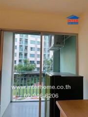 Sliding glass door in living room opening to a balcony with view of buildings