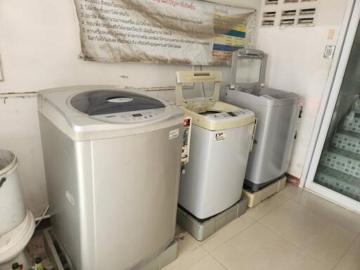 A laundry room with three washing machines