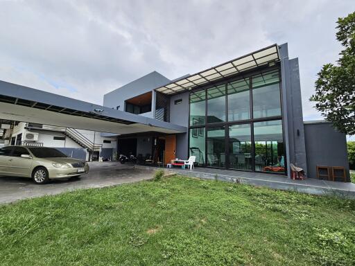 Modern house front view with large glass windows and carport