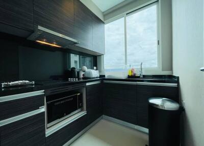 Modern kitchen with dark cabinets, built-in oven, and large window