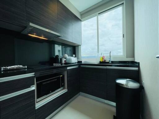 Modern kitchen with dark cabinets, built-in oven, and large window