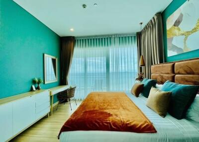 Modern bedroom with large window, a desk, and colorful decor