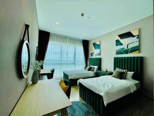 Spacious bedroom with two beds, large window, and modern decor.