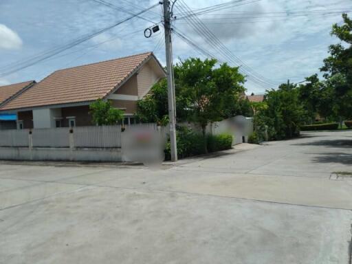 Street view of a residential house with a tiled roof and surrounding greenery