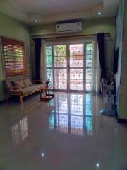 Bright living room with couch, coffee table, air conditioning, and large windows.