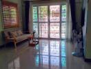 Bright living room with couch, coffee table, air conditioning, and large windows.