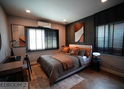 Modern bedroom with contemporary decor featuring a bed, desk, and window blinds