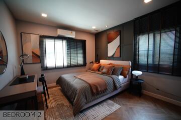 Modern bedroom with contemporary decor featuring a bed, desk, and window blinds