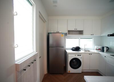 Modern kitchen with white cabinets, stainless steel fridge, and washing machine