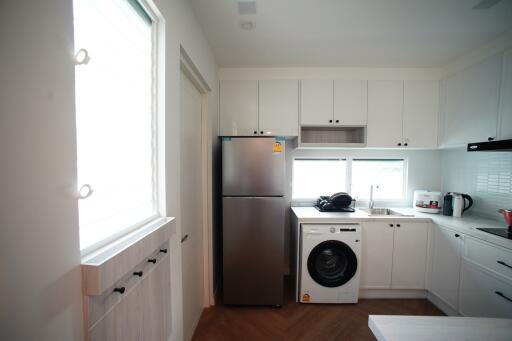 Modern kitchen with white cabinets, stainless steel fridge, and washing machine