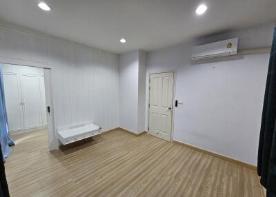 Spacious bedroom with wooden floor, white walls, and built-in closet