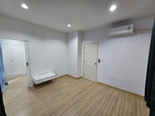 Spacious bedroom with wooden floor, white walls, and built-in closet