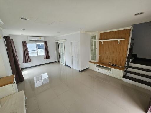 Modern spacious living room with tiled floors, large windows, and a staircase