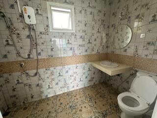 Bathroom with square tiles, electric water heater, small window, round mirror, and basin